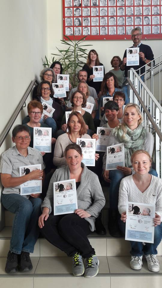 Alle Teilnehmer sitzen auf einer Treppe und halten ihr Zertifikat hoch. 